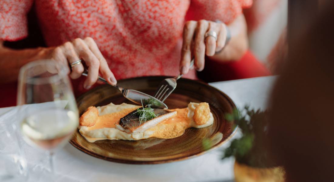 Eine Frau schneidet ihre Mahlzeit auf einem braunen Teller in einem Restaurant.