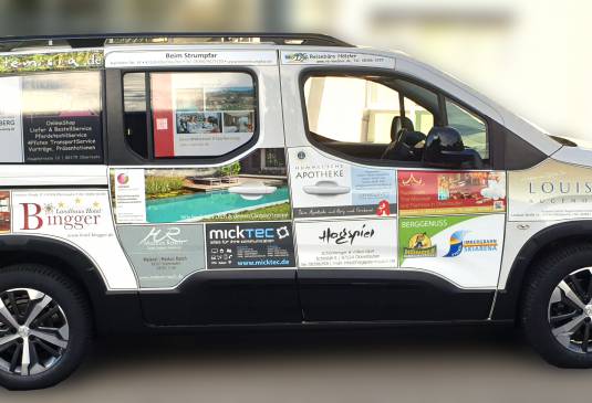 Seitenansicht auf ein Auto mit verschiedenen Werbeflächen foliert.