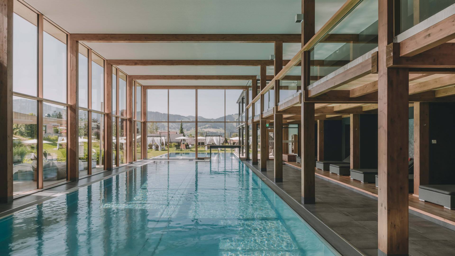 Großer Pool im Wellnessbereich mit Holzbalken und großer Fensterfront.