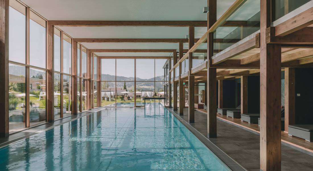 Großer Pool im Wellnessbereich mit Holzbalken und großer Fensterfront.