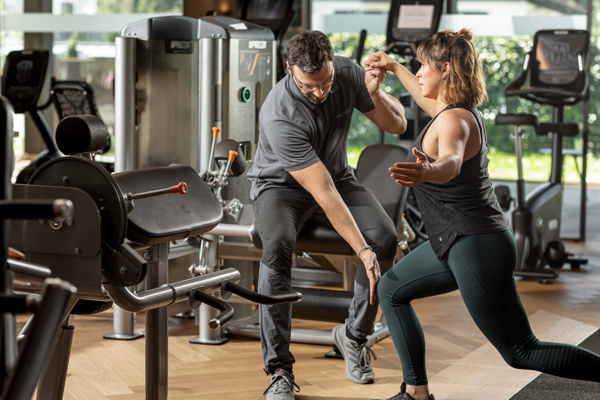 Eine Frau bekommt von einem Mann Hilfestellung bei einer Körperübung im Rahmen einer Reha in Oberstaufen.