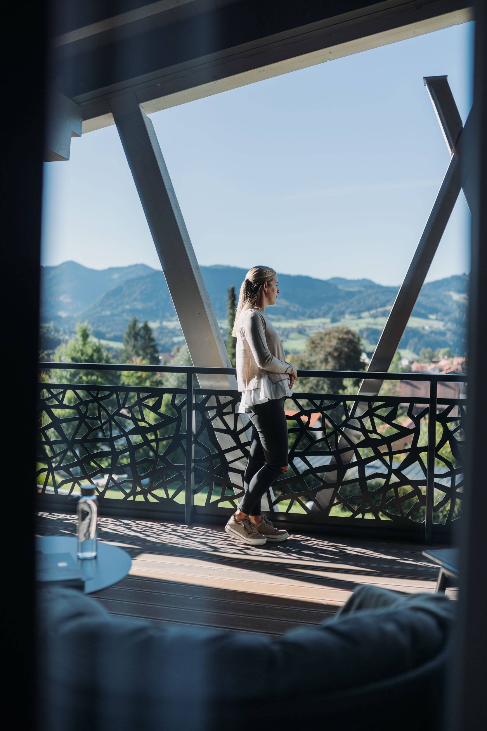 Eine Frau steht vor einem Bergpanorama auf einem Balkon als Teil einer Schrothkur in Oberstaufen.