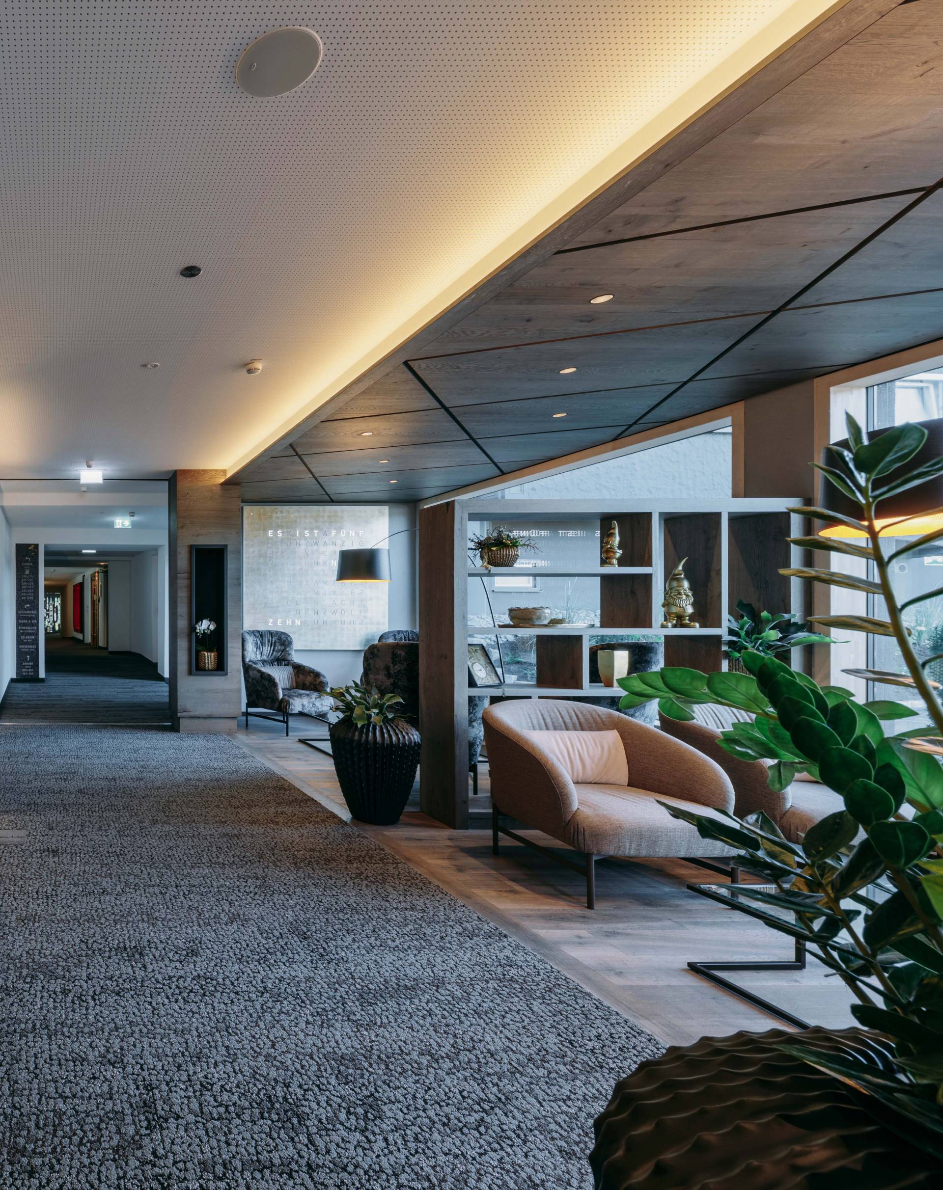 Gemütlicher Loungebereich mit Sesseln, indirekter Beleuchtung und Pflanzen.