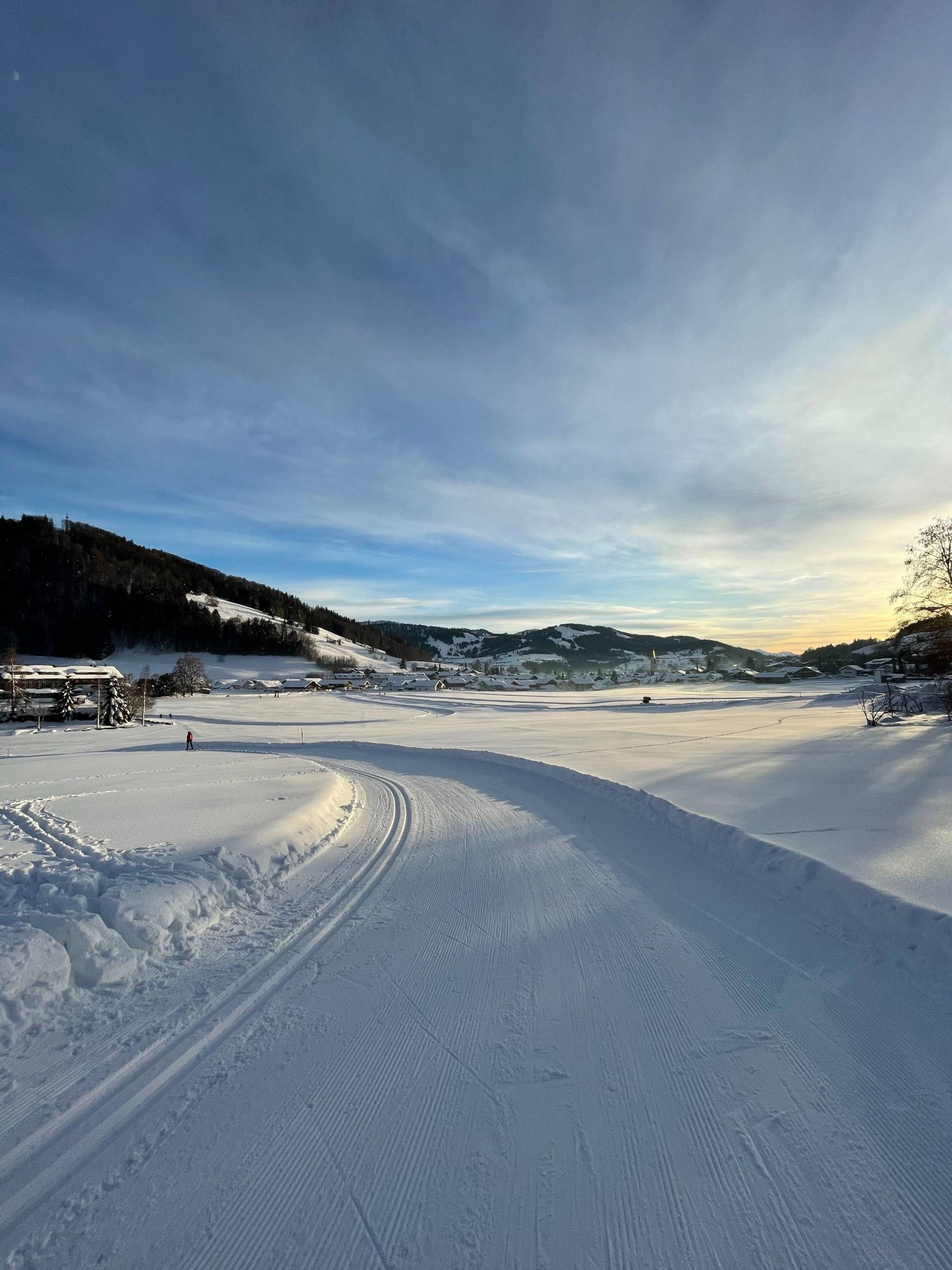 Eine schneebedeckte Landschaft mit Bergpanorama, welche Lust auf Winterurlaub in Bayern macht.