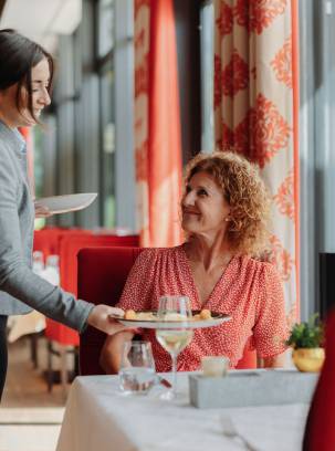 Zwei Frauen erhalten in einem Restaurant von der Kellnerin ihre Mahlzeiten.