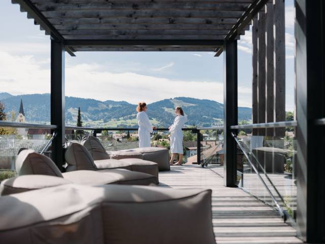 Zwei Frauen im weißen Bademantel auf der Terrasse im Wellnessgarten.