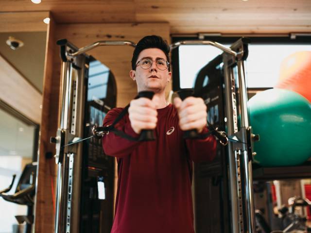 Mann in roten Shirt trainiert an einem Fitnessgerät.