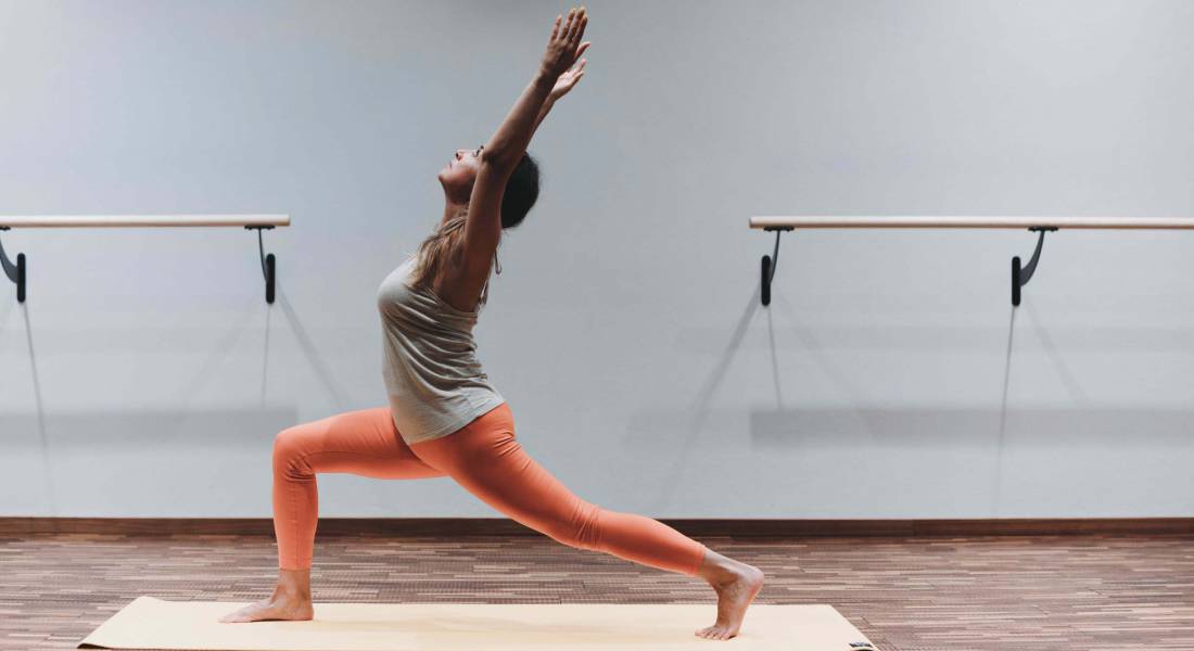 Eine Frau in auffälliger Sporthose macht Yoga in einem Studio als Teil ihres Aktivurlaub im Allgäu.