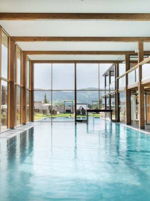 Großzügiger Wellnessbereich mit Pool vor großer Glasfront als Ort für Wellness in Oberstaufen.