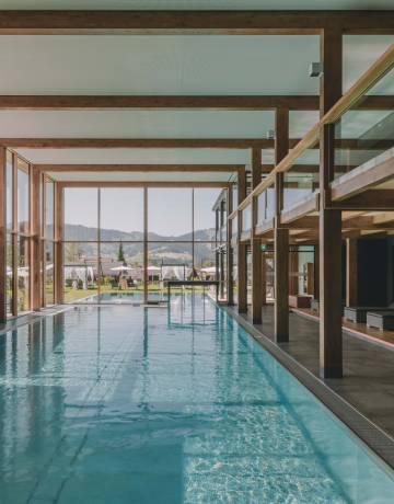 Großer Pool im Wellnessbereich mit Holzbalken und großer Fensterfront.