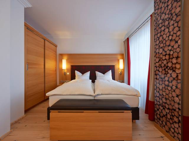 Sicht in ein holzverkleidetes Hotelzimmer mit Doppelbett.