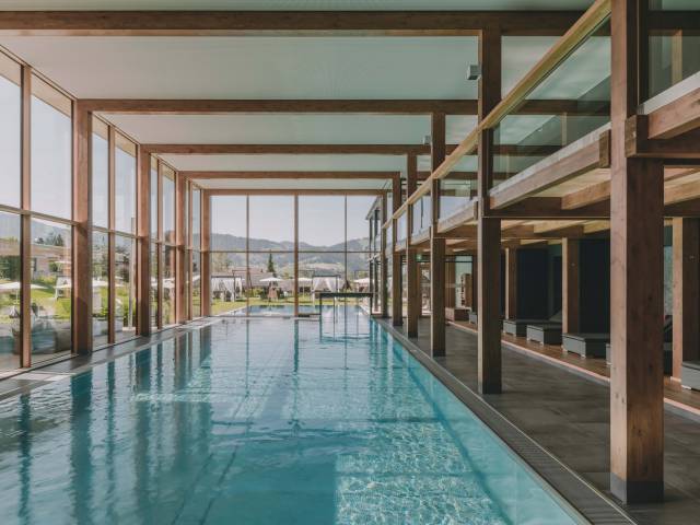 Großer Pool im Wellnessbereich mit Holzbalken und großer Fensterfront.