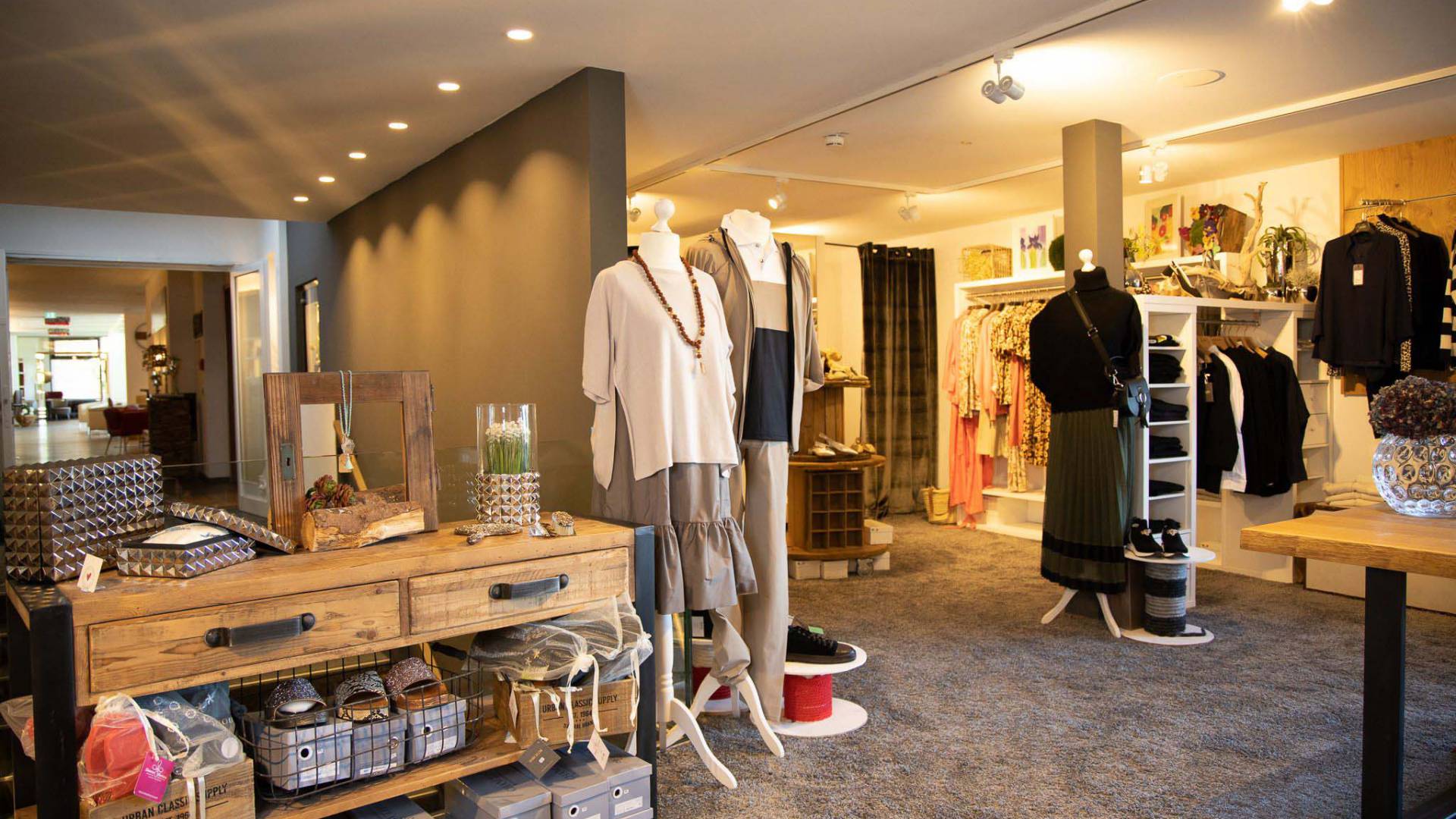 Eine gemütlich eingerichtete Boutique in welcher diverse Kleidungsstücke und Accessoires ausgestellt sind.