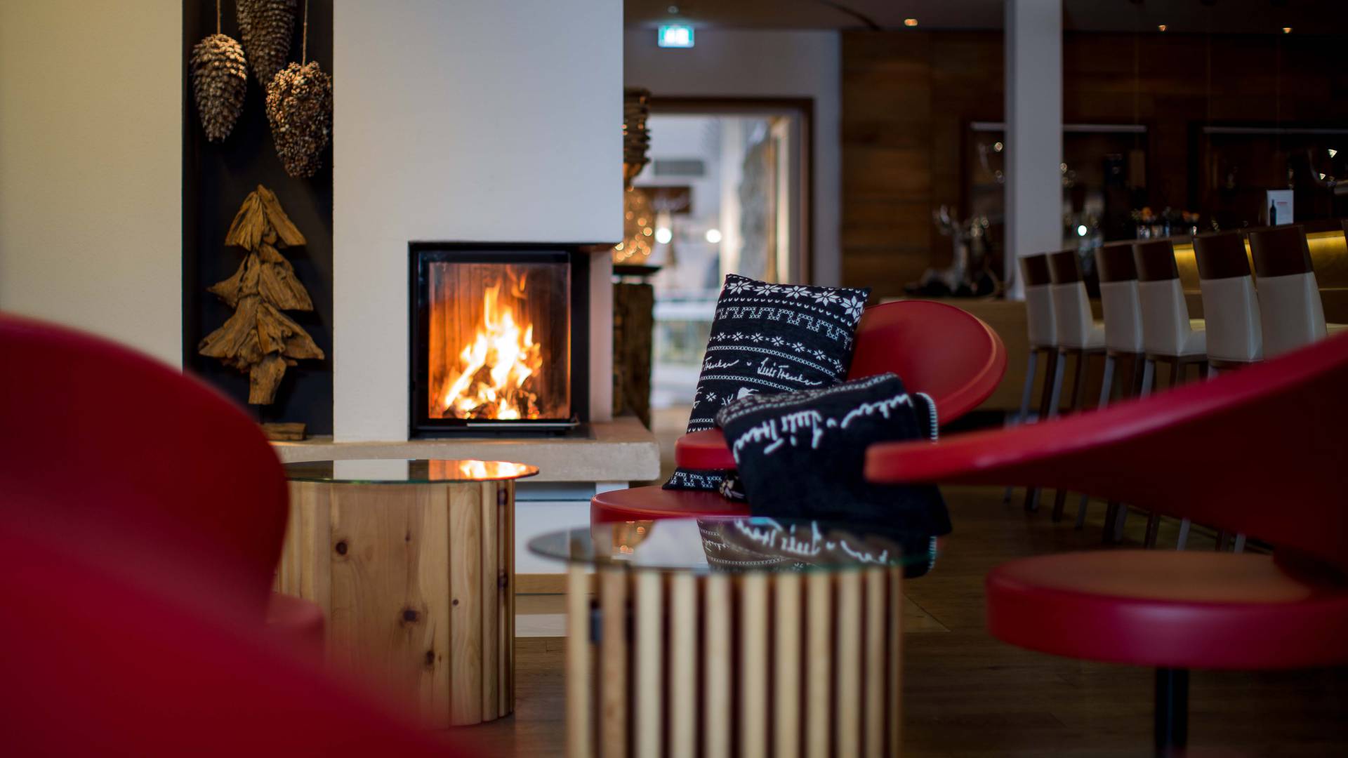Eine gemütliche Bar mit geschlossenem Kaminfeuer und roten Sitzmöbeln macht Lust auf einen Winterurlaub in Bayern.